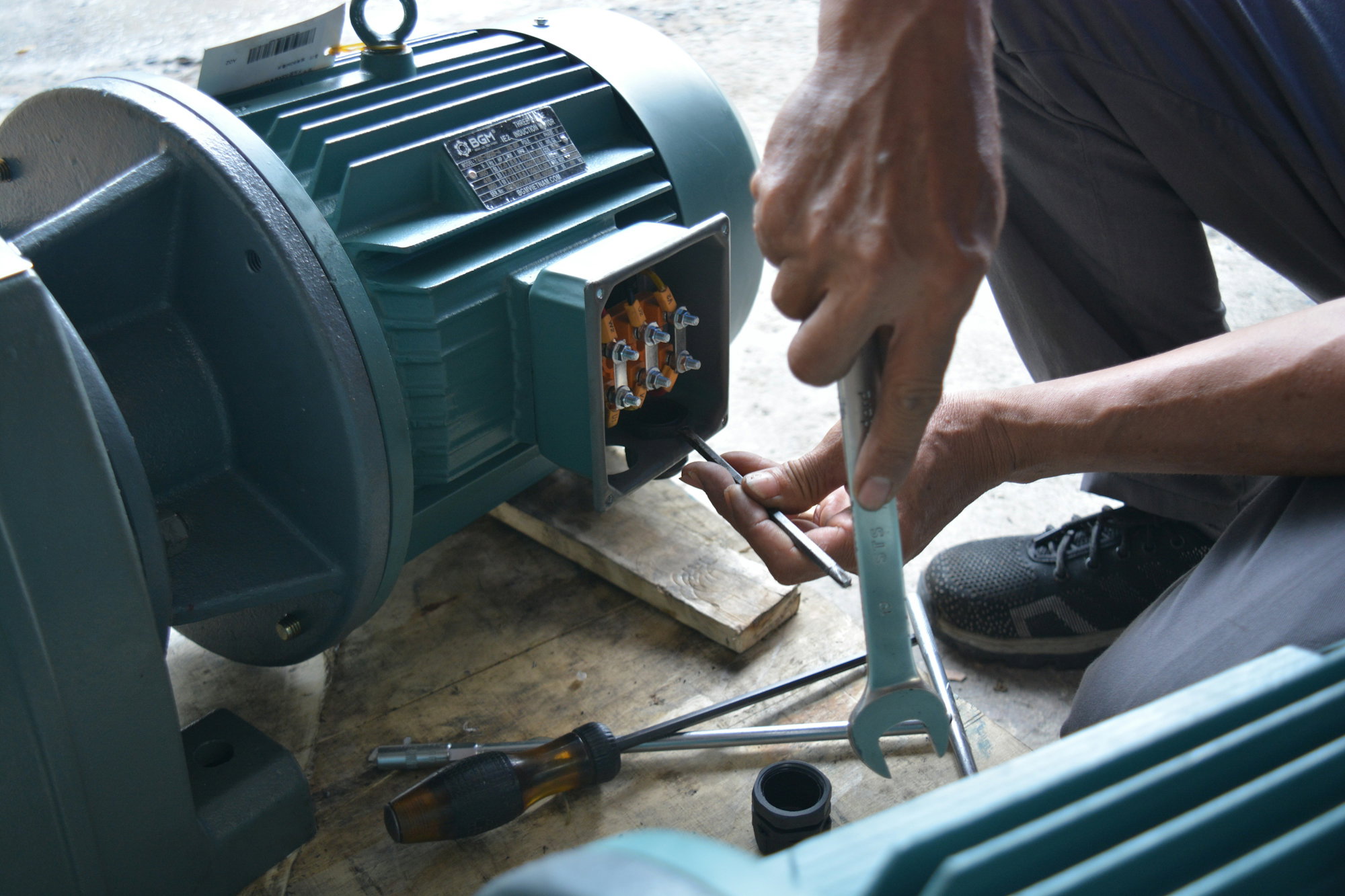 a-man-working-on-a-machine-with-a-wrench.jpg a man working on a machine with a wrench